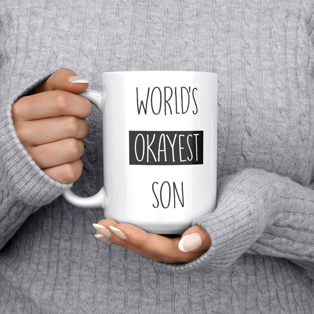 Okayest_son_15ozWhiteMugLifestyleLHChest_Mockup.png_15683848